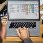 Profissional usando Excel para melhorar resultados empresariais em planilha no laptop